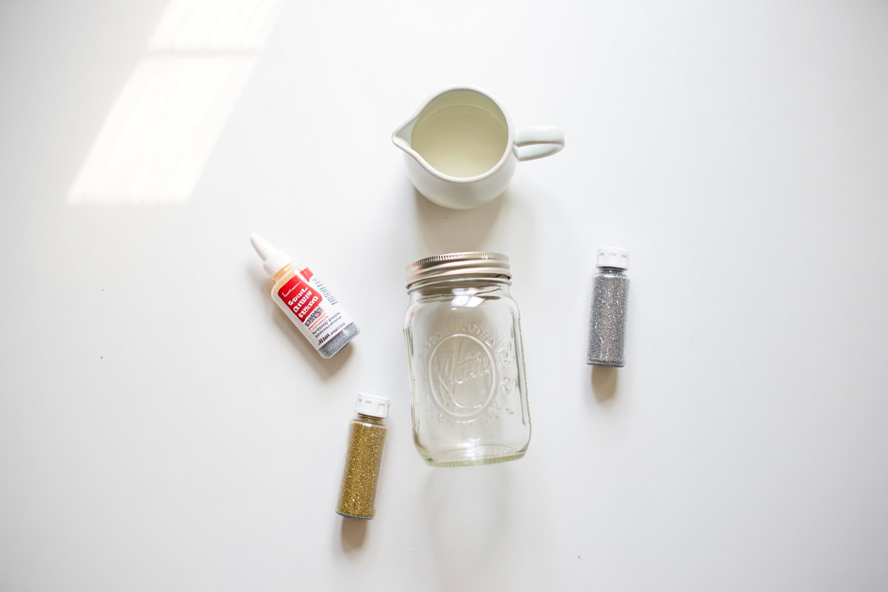 Materials for making a glitter jar: clear jar, glitter, glue, and water