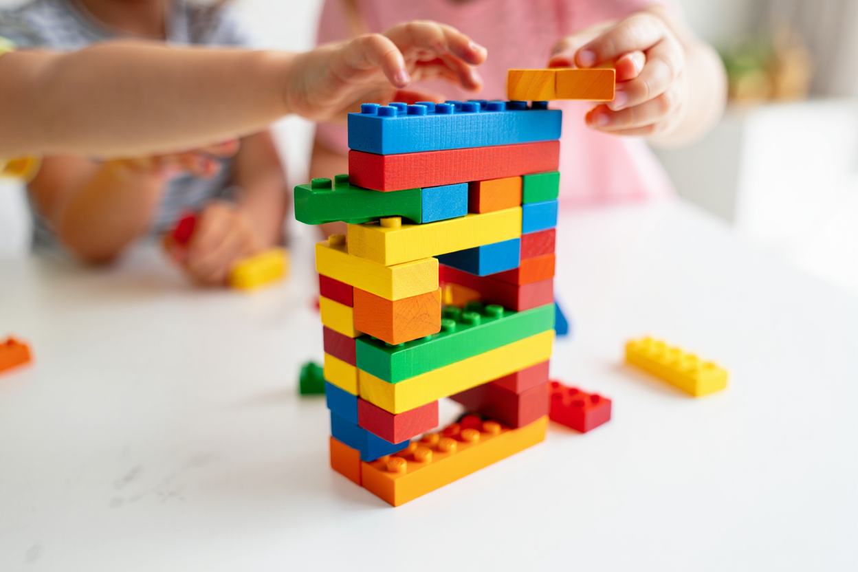 Children's hands building a colorful block tower together, cooperative teamwork activity
